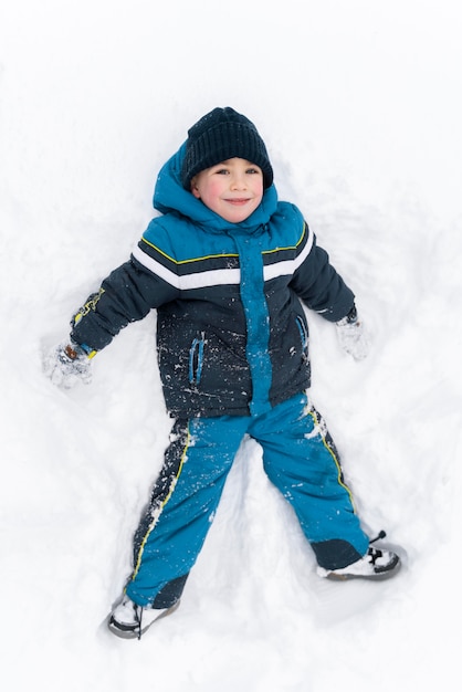 Cerrar n niño feliz jugando en la nieve.