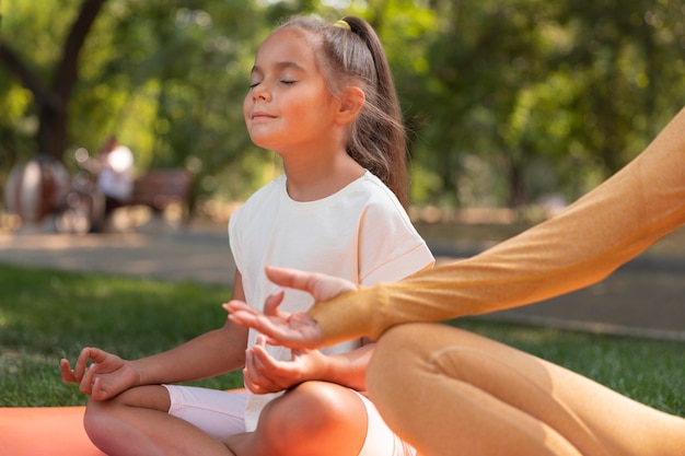 Cerrar niña meditando al aire libre