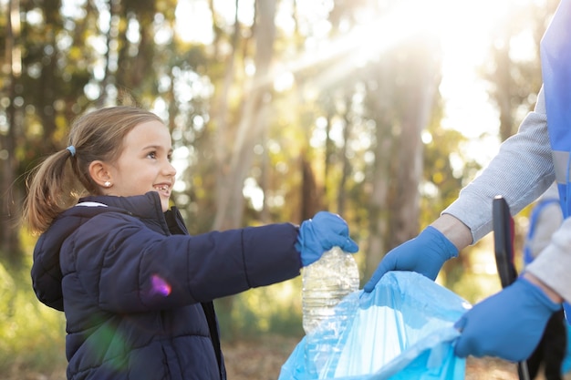 Foto cerrar niña sonriente recogiendo basura