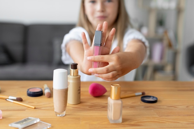 Foto cerrar niña sosteniendo brillo de labios