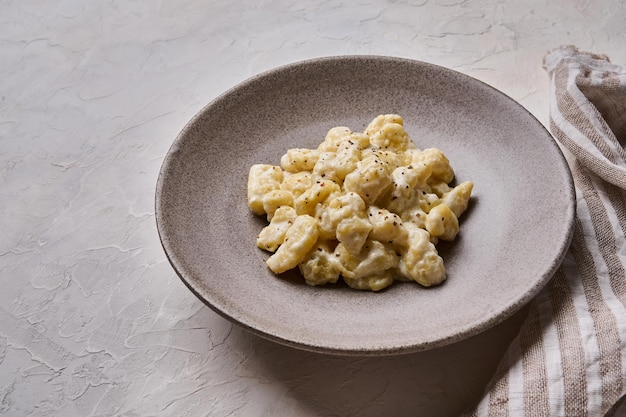 Cerrar ñoquis caseros preparados con papa y masa de harina integral con salsa de crema en gris