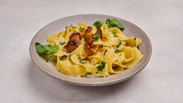 Cerrar panorámica pappardelle de pasta con champiñones, rebozuelos, queso y perejil en la parte superior de la placa