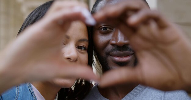 Cerrar pareja africana haciendo forma de corazón con las manos al aire libre