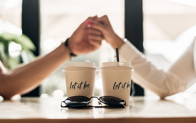 Cerrar pareja amorosa disfrutando de tiempo juntos sentados en una cafetería, tomados de la mano