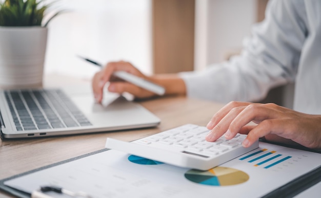 Foto cerrar la persona de negocios está sentada en una calculadora con un gráfico en la oficina del concepto de contabilidad financiera