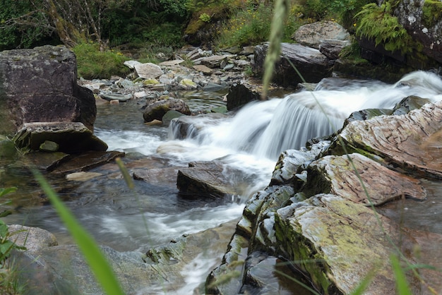 Cerrar piedras del río de montaña con corriente de agua congelada de larga exposición