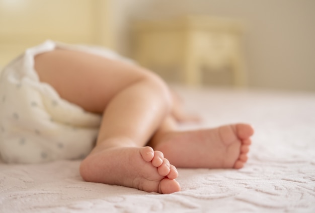 Cerrar las piernas del bebé acostado en la cama en casa
