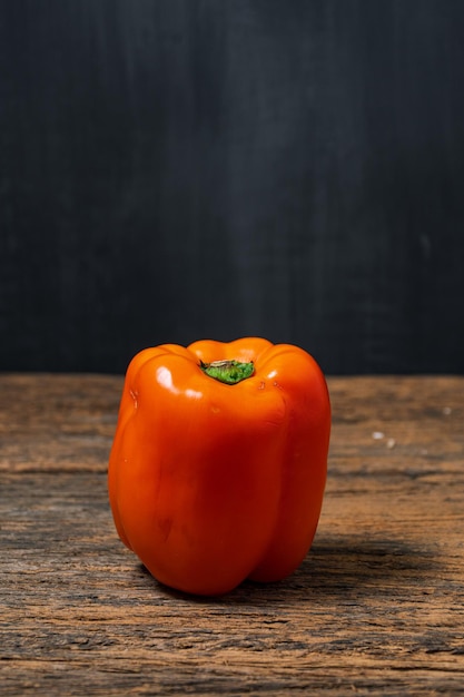 Cerrar los pimientos naranjas en la mesa de madera con espacio en blanco de copyspace para el concepto de comida sana de texto