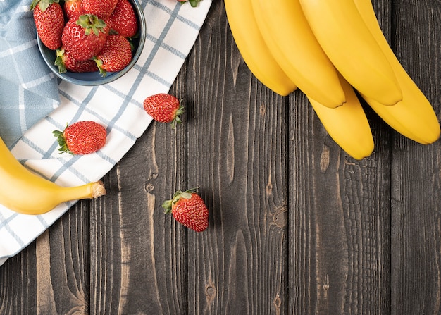 Foto cerrar plátanos con fresas sobre un fondo de mesa de madera