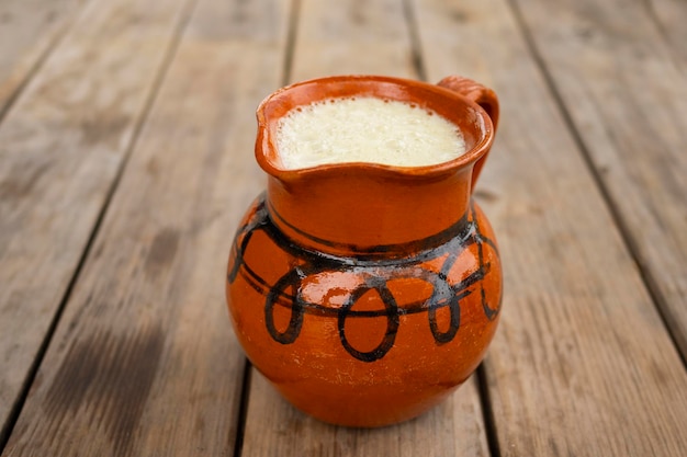 Foto cerrar pulque bebida artesanal mexicana en una jarra de arcilla sobre una mesa de madera enfoque selectivo