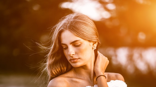 Cerrar retrato de una hermosa niña con cabello sano soplado por el viento disfrutando de su tiempo al aire libre en el parque