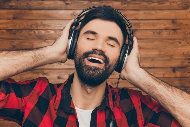 Cerrar retrato de hombre feliz escuchando música y cantando con los ojos cerrados