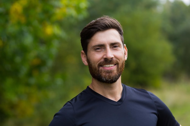 Cerrar retrato joven barbudo feliz de pie en la naturaleza entre los árboles del bosque se relaja, respira aire fresco y cierra los ojos. Hombre disfruta de una vida de paz tranquila, tranquila en el parque. Al aire libre. Felicidad