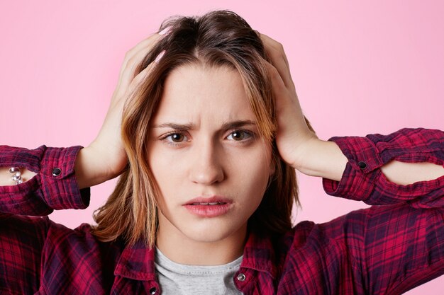 Foto cerrar retrato de modelo femenino estresante toca la cabeza y sufre de dolor de cabeza, se ve frustrado