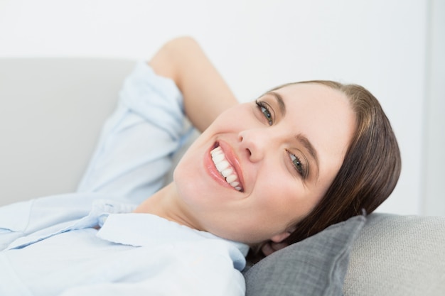 Cerrar el retrato de una mujer bien vestida sonriente relajante en el sofá