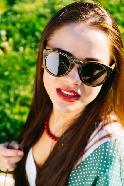 Cerrar rostro de mujer en gafas de sol, gafas de madera, blanqueamiento