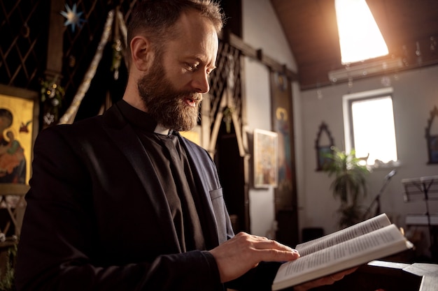 Foto cerrar el sacerdote leyendo la biblia