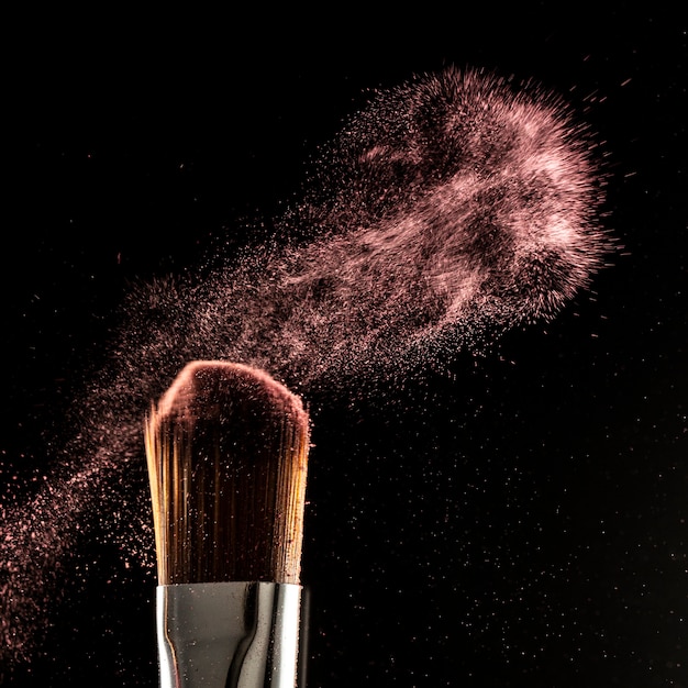 Foto cerrar salpicaduras de polvo y pincel para maquilladora o blogger de belleza