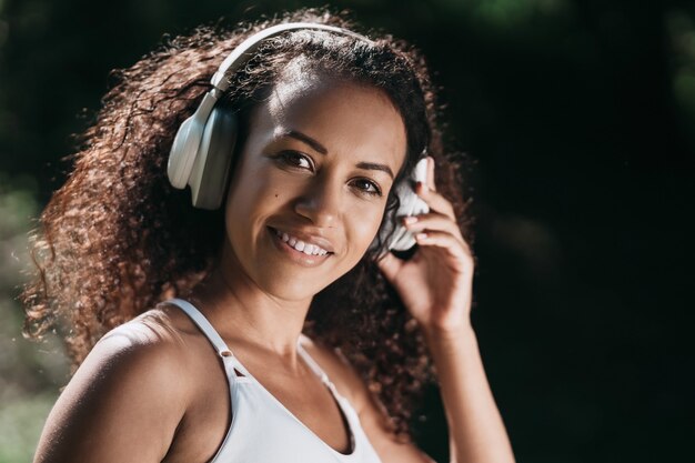 Cerrar sonriente mujer atlética usando audífonos