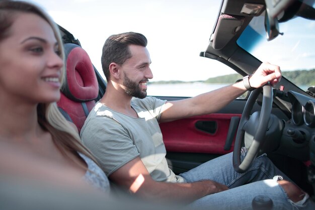 Cerrar sonriente pareja sentada en un cartravel convertible juntos