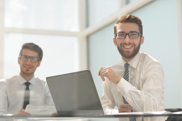 Cerrar sonrientes colegas de negocios sentados en Deskphoto con espacio para texto