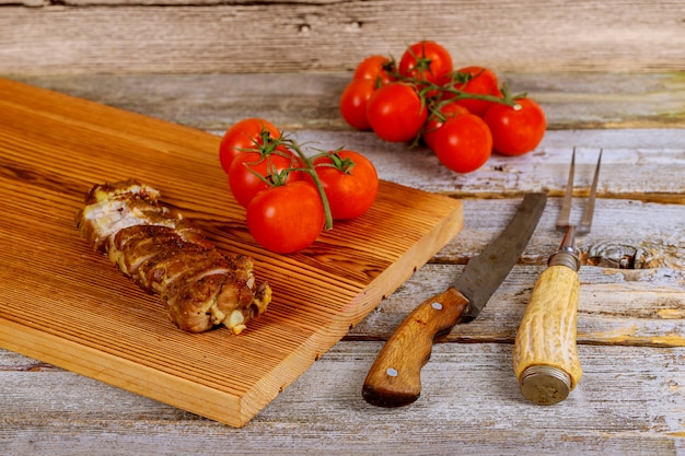 Cerrar en tablero de madera con filete de cerdo a la parrilla junto a tomates cherry en mesa de madera