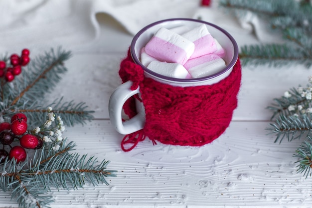 Cerrar una taza de chocolate caliente con malvaviscos en Navidad decorado mesa de madera blanca