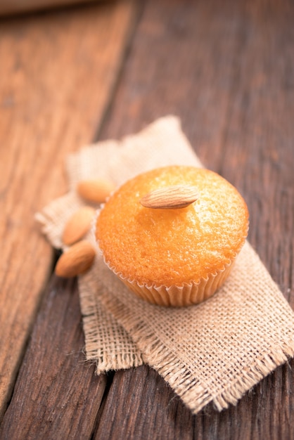 Cerrar una taza de pastel de almendra contra tela de saco en mesa de madera