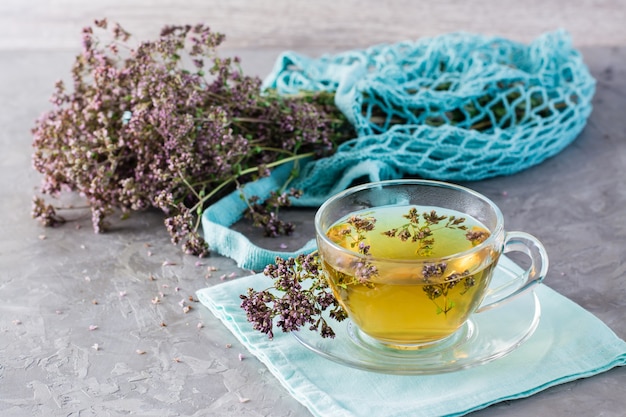 Cerrar una taza de té con orégano y un manojo de hierbas secas