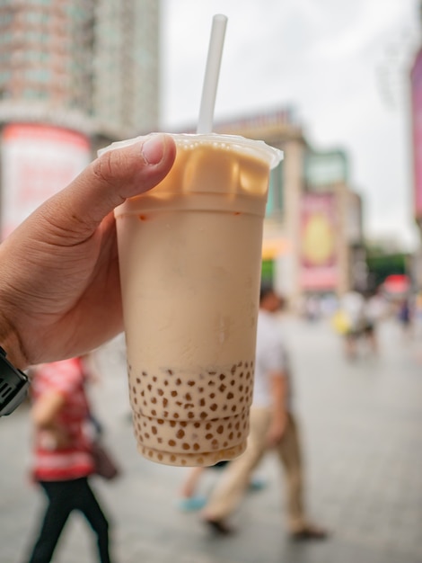 Cerrar té de burbujas en la mano del turista en una calle peatonal en China