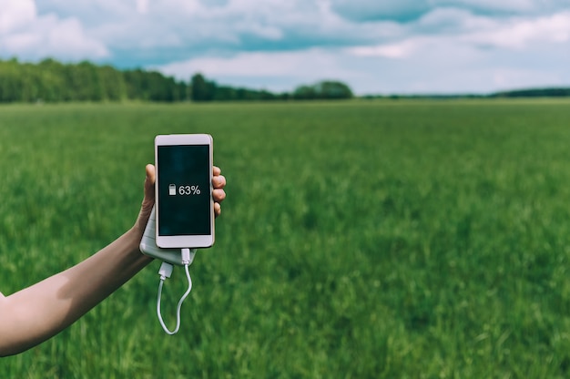 Cerrar en el teléfono móvil en blanco con el banco de energía en la mano