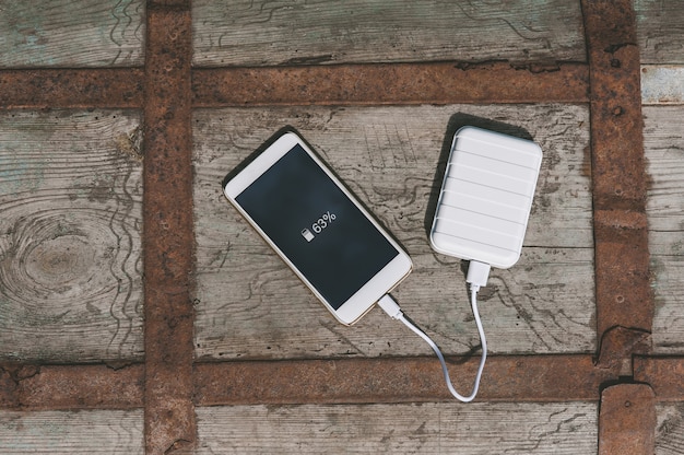 Cerrar en el teléfono móvil en blanco con el banco de energía en la mano