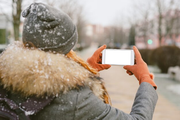 Cerrar en el teléfono móvil en blanco sostenido en la mano