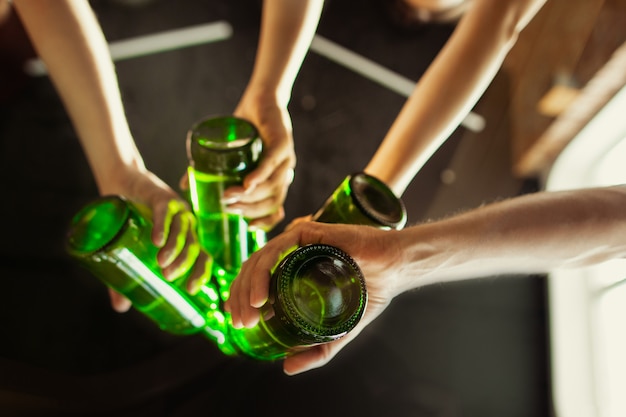 Cerrar tintineo. Joven grupo de amigos bebiendo cerveza, divirtiéndose, riendo y celebrando juntos. Mujeres y hombres con vasos de cerveza. Oktoberfest, amistad, unión, concepto de felicidad.