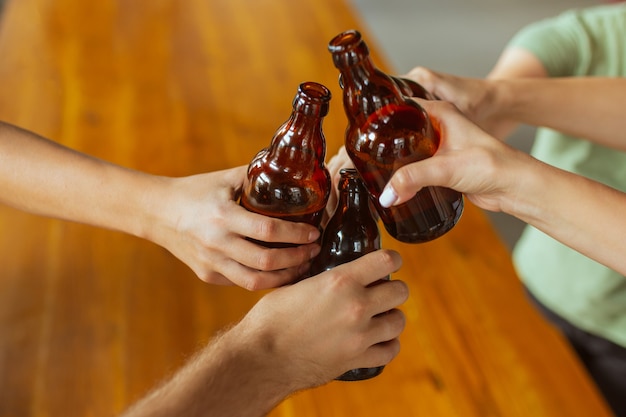 Cerrar tintineo. Joven grupo de amigos bebiendo cerveza, divirtiéndose, riendo y celebrando juntos. Mujeres y hombres con vasos de cerveza. Oktoberfest, amistad, unión, concepto de felicidad.