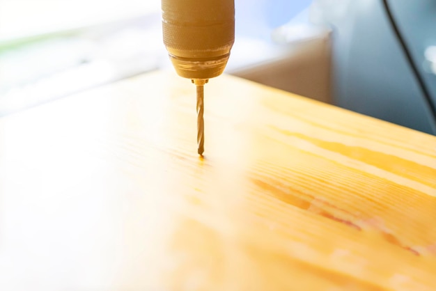 Cerrar trabajador haciendo un agujero en la superficie de madera en casa utilizando taladro f