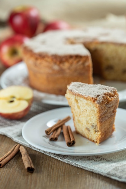 Cerrar un trozo de bizcocho o bizcocho con manzanas tan suaves y deliciosas en rodajas con ingredientes canela huevos harina manzanas en la mesa de madera Concepto de panadería casera para fondo y papel tapiz