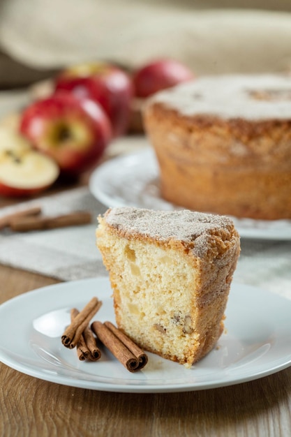 Cerrar un trozo de bizcocho o bizcocho con manzanas tan suaves y deliciosas en rodajas con ingredientes canela huevos harina manzanas en la mesa de madera Concepto de panadería casera para fondo y papel tapiz