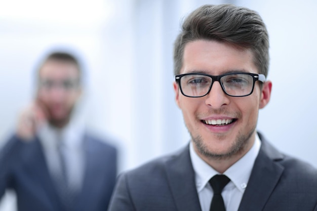 Cerrar upsmiling joven empresario en el fondo de la oficina