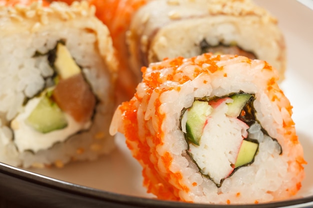 Cerrar Uramaki California Sushi roll con arroz nori trozos de aguacate pepino palitos de cangrejo