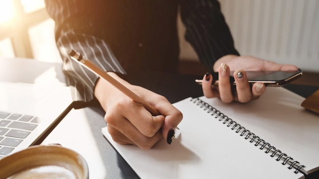 Cerrar vista de empresaria escribiendo en el cuaderno en un lugar de trabajo cómodo