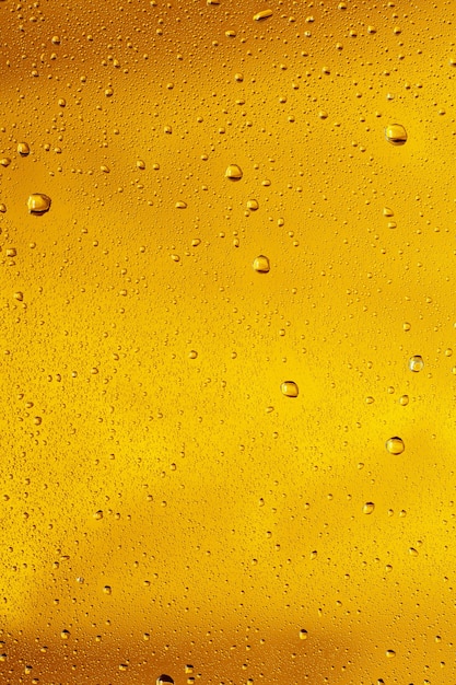 Cerrar vista de gotas frías en el vaso de cerveza de fondo. Textura de bebida alcohólica de enfriamiento con macro burbujas en la pared de vidrio. Efervescente o flotando hasta la parte superior de la superficie. De color dorado.