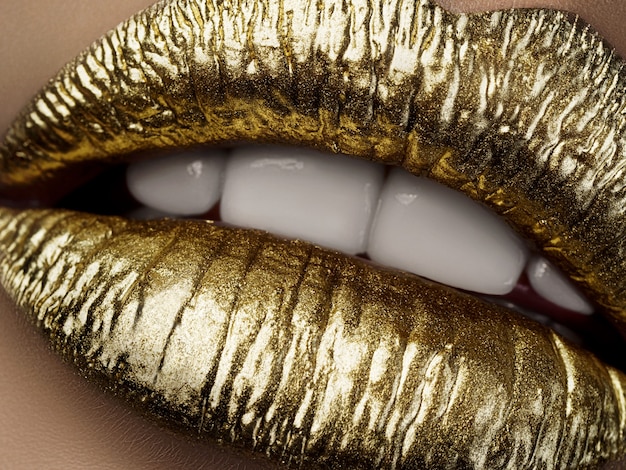 Cerrar vista de labios de mujer hermosa con lápiz labial dorado metálico