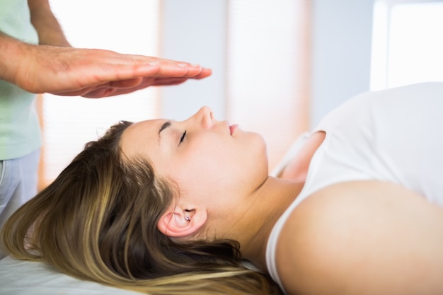 Cerrar vista de mujer embarazada recibiendo tratamiento de reiki