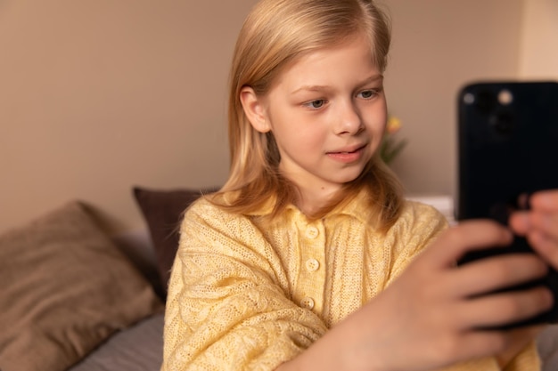 Cerrar vista de niña haciendo foto y mirando el teléfono