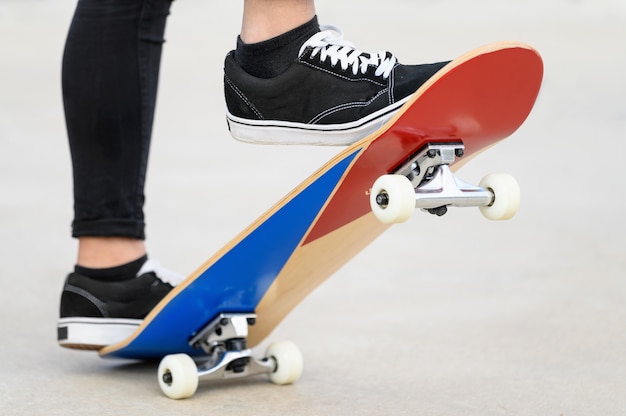 Cerrar la vista de los pies del adolescente en una patineta lista para comenzar un paseo sobre la media tubería.