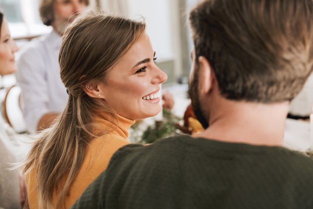 Cerrar vista posterior de una encantadora pareja abrazándose mientras está sentado en la mesa de la cena con la familia