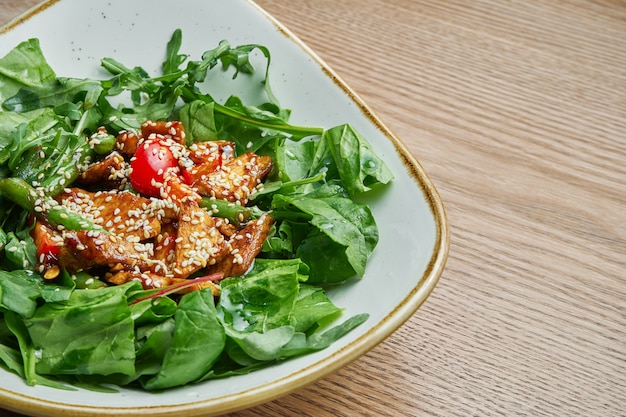 Cerrar vista sobre sabrosa ensalada ligera cálida con tomate, pavo, una mezcla de verduras en un elegante tazón gris. Sabroso almuerzo. Fondo de madera