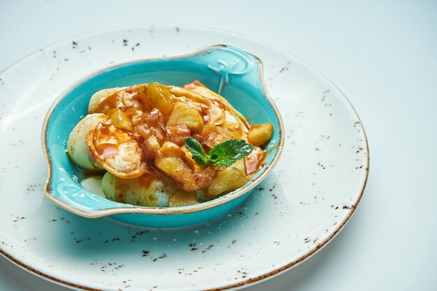 Cerrar vista sobre sabrosos crepes franceses rellenos de requesón y mermelada amarilla en un plato de cerámica en gris. panqueques ucranianos