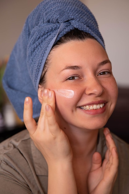 Cerrar vista de sonrisa mujer con crema en la cara